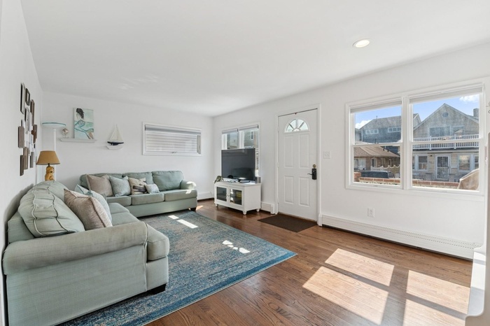 Spacious Living area with a baseboard radiator, healthy amount of natural light, dark wood finished floors, baseboards, and recessed lighting
