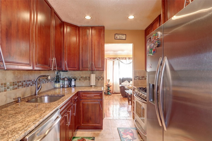 Kitchen featuring stainless steel appliances, a sink, tasteful backsplash, light stone counters, and recessed lighting