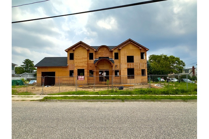 Unfinished property with an attached garage and a fenced front yard