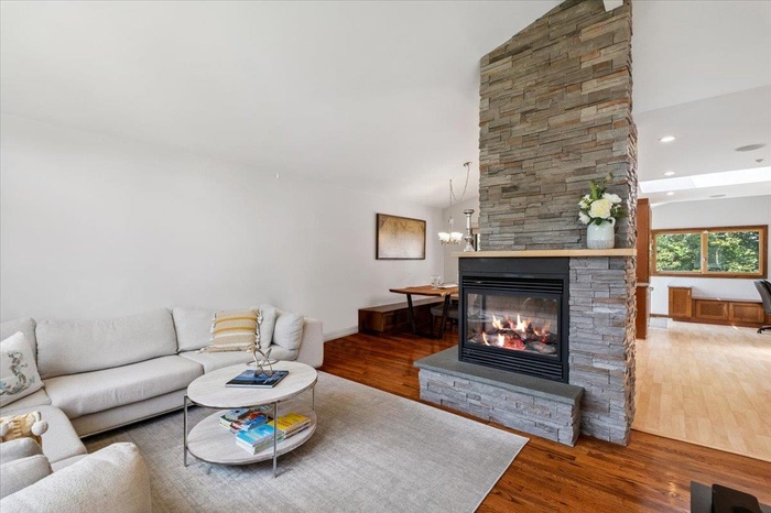Living area featuring wood finished floors, a fireplace, recessed lighting, high vaulted ceiling, and a chandelier