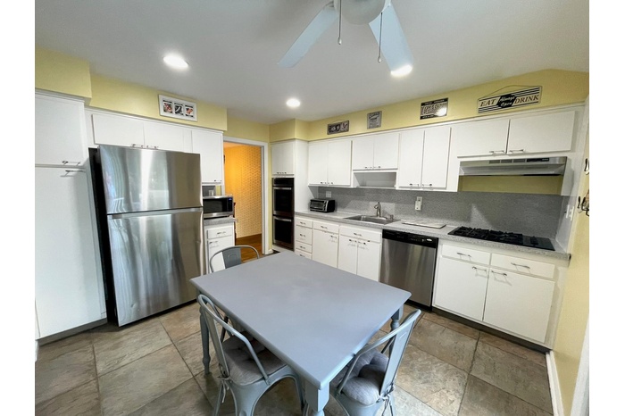 Kitchen with stainless steel appliances, white cabinetry, backsplash, recessed lighting, and light countertops