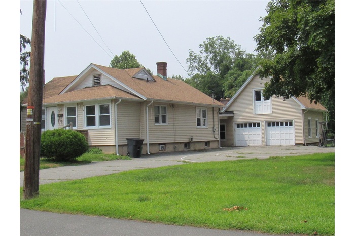 View of front of property with concrete driveway, a front lawn, a garage, and a chimney