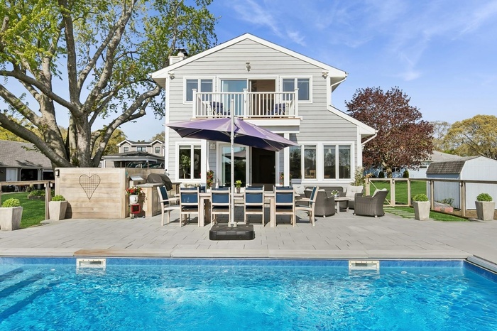 Rear view of house featuring a balcony, outdoor lounge area, a patio area, a storage shed, and a chimney