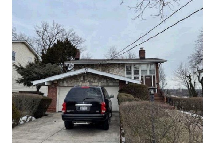 View of front of house featuring a chimney and driveway