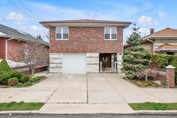 Traditional home featuring stone siding, brick siding, driveway, and a garage