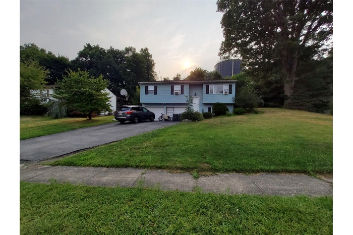 Split foyer home with an attached garage, driveway, and a yard