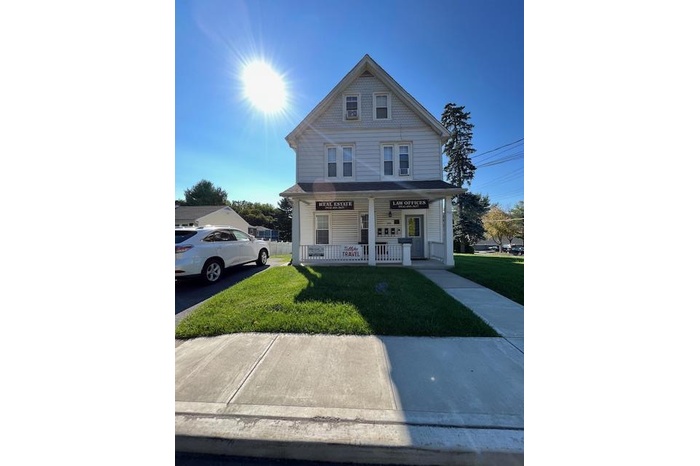 View of front of property featuring covered porch and a front yard