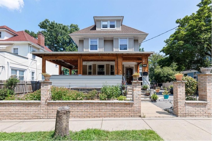 American foursquare style home featuring covered porch and a shingled roof