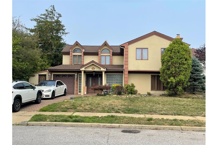 View of front of home featuring decorative driveway, a garage, stucco siding, and a front lawn