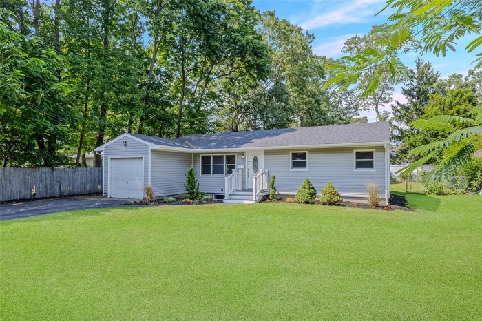 View of front of house featuring driveway, an attached garage, and roof with shingles