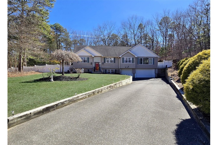 Bi-level home with driveway, a front yard, an attached garage, and fence