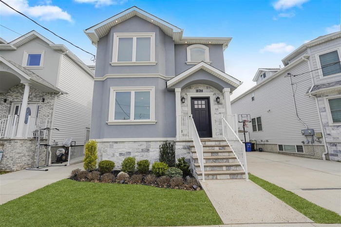 View of front of home featuring stone siding, a front lawn, and stucco siding