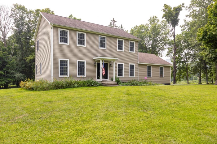 Colonial-style house featuring a front yard and roof with shingles