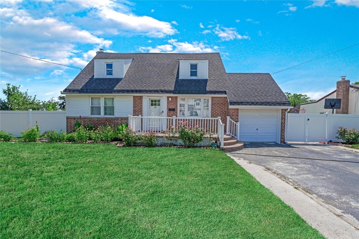 View of front of property featuring brick siding, asphalt driveway, an attached garage, and a shingled roof