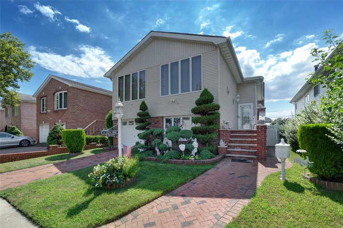 View of front of house with an attached garage, brick siding, a front yard, and driveway