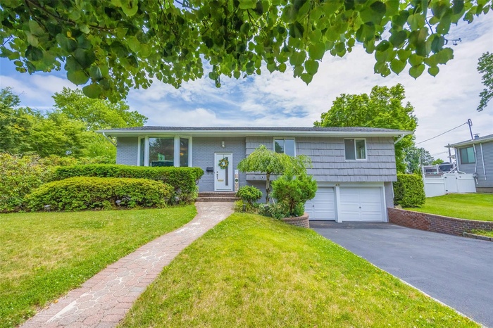 Split foyer home featuring a garage, asphalt driveway, and a front lawn