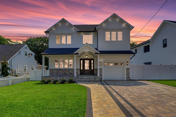 View of front of house with decorative driveway, board and batten siding, a shingled roof, and stone siding