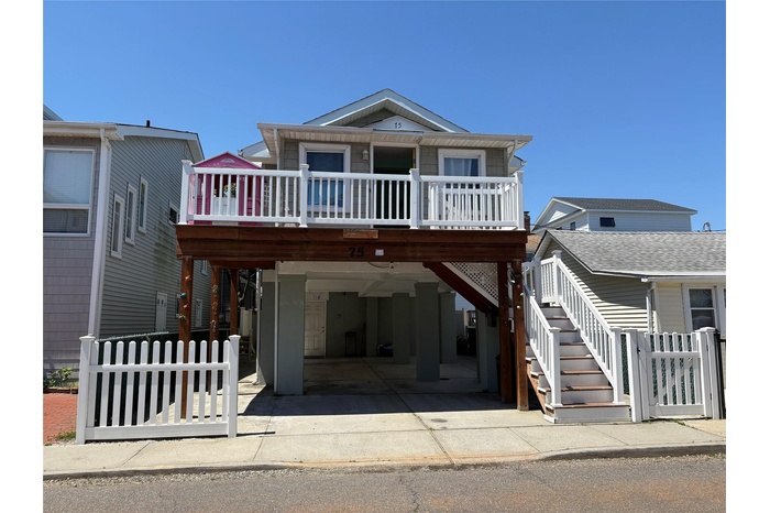 Beach home featuring stairway, a garage, driveway, and a deck