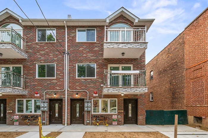 View of front facade with a balcony and brick siding