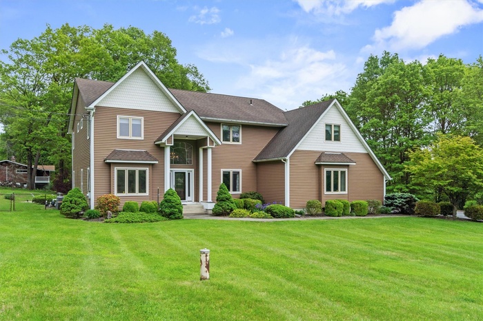 View of front facade featuring a front lawn and a shingled roof