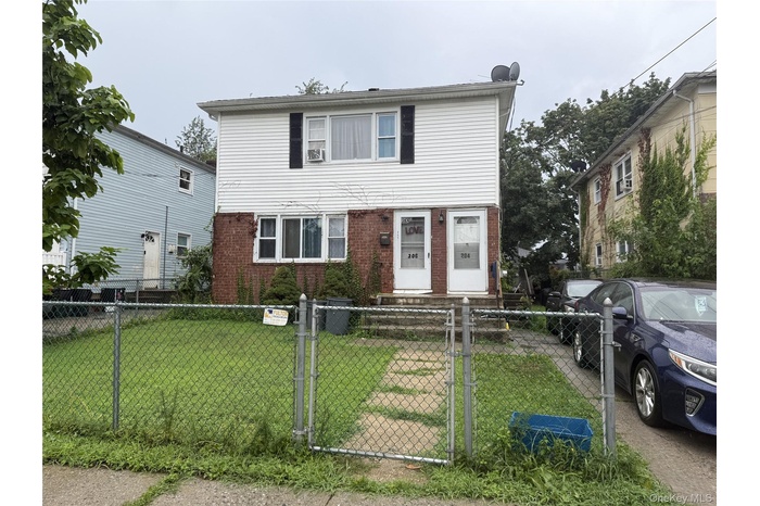 View of front of house featuring brick siding, a gate, and a fenced front yard