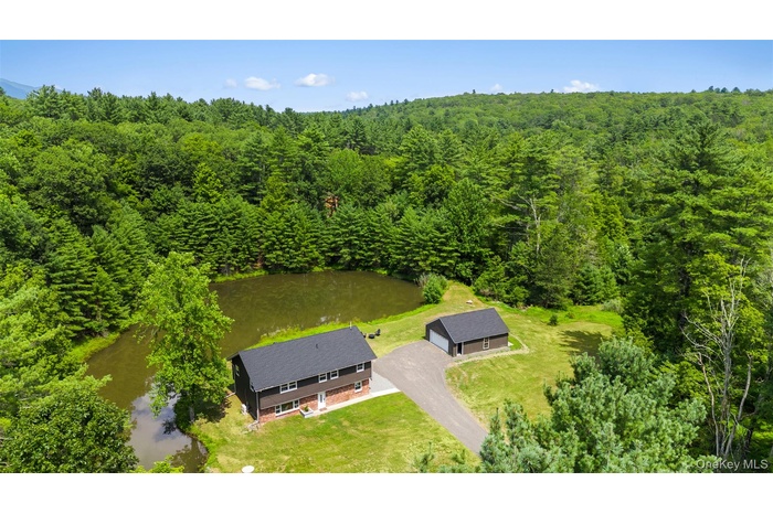 View from above of property with a forest and a large body of water
