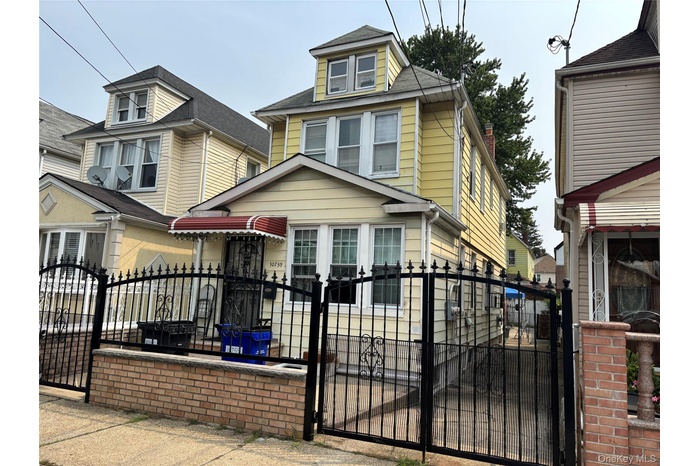 Traditional style home featuring a gate, a fenced front yard, and roof with shingles
