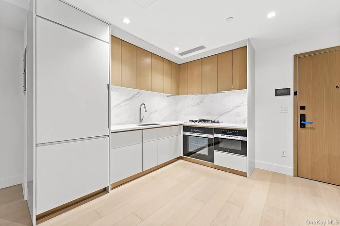 Kitchen with light countertops, oven, light wood-style floors, tasteful backsplash, and recessed lighting