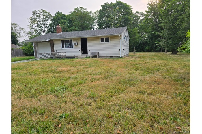 View of front of property with a garage, a chimney, a front yard, and crawl space