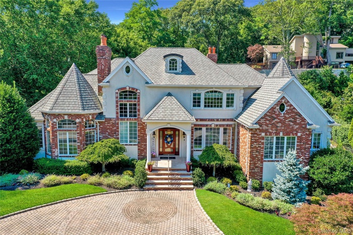 View of this Story Book style home with stucco and brick siding, paver driveway