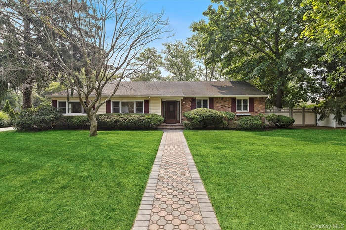 Ranch-style home with roof with shingles and brick siding