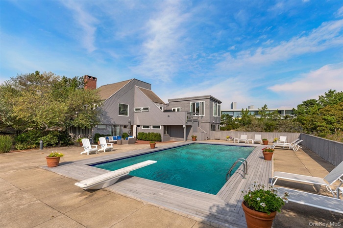 View of pool with an outdoor living space, a diving board, a deck, stairway, and a patio area