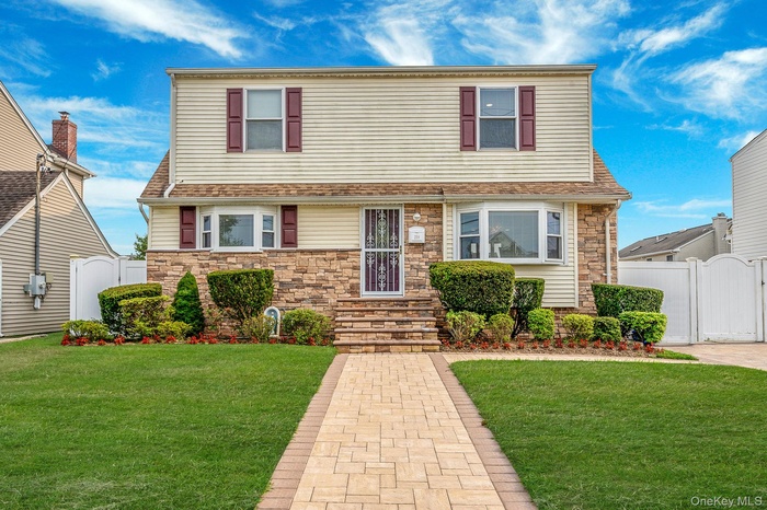 View of front of property featuring a gate, stone siding, and roof with shingles