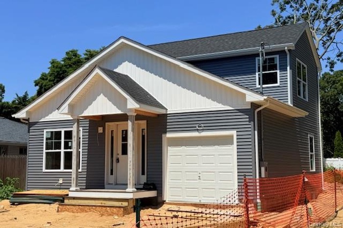 View of front of home with a shingled roof and a garage