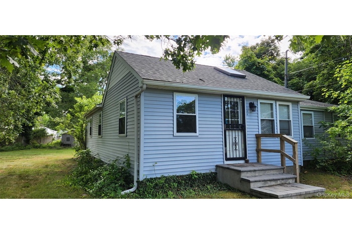 Bungalow-style home with roof with shingles and a front lawn