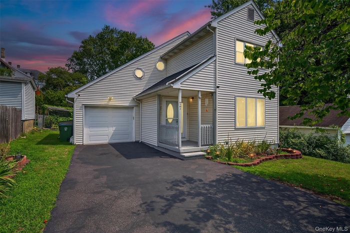 View of front facade with a garage, driveway, and covered porch