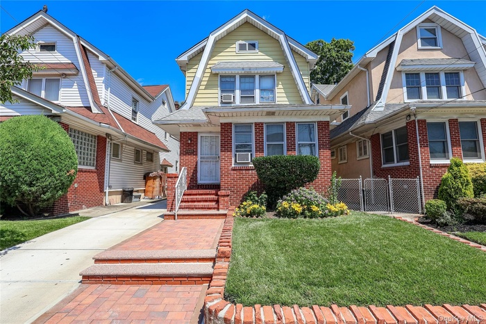 Colonial inspired home with brick siding, a gambrel roof, and concrete driveway