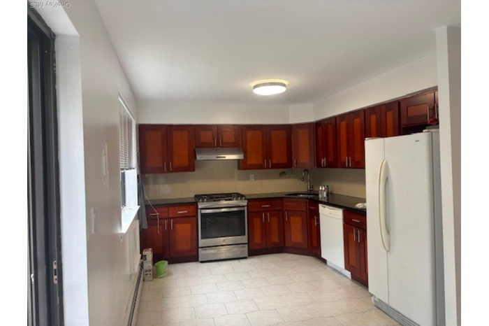 Kitchen with range, refrigerator, dark brown cabinets, under cabinet range hood, and dark countertops
