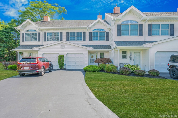 View of front of property featuring driveway, a front yard, a chimney, and roof with shingles