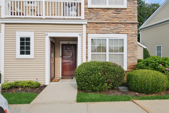 View of exterior entry with a balcony and stone siding