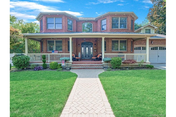 Traditional home with a porch, brick siding, a front lawn, and driveway