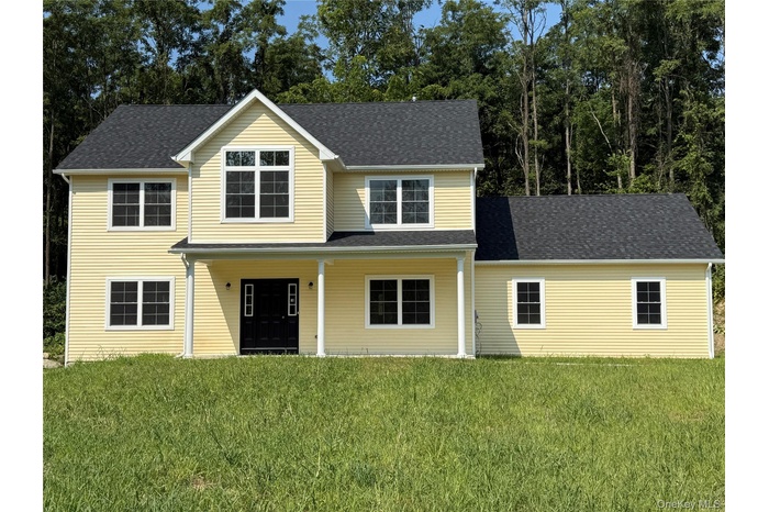 Traditional-style home featuring a front yard and roof with shingles