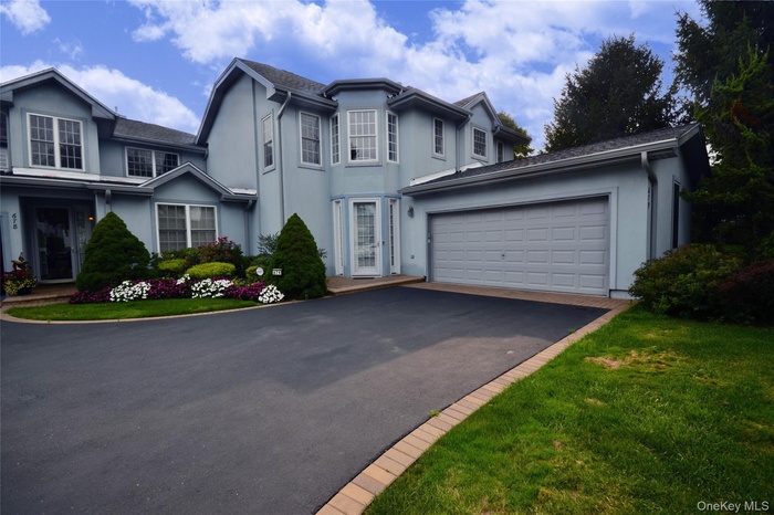 Traditional home with stucco siding, asphalt driveway, and an attached garage