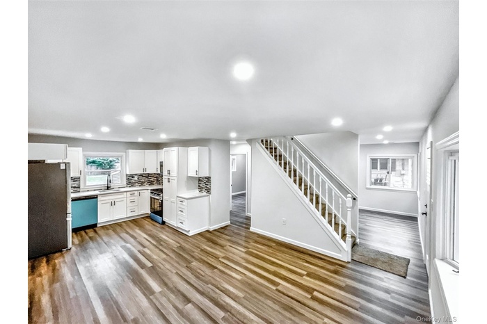 Kitchen featuring stainless steel appliances, backsplash, wood finished floors, white cabinetry, and recessed lighting
