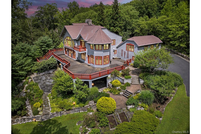 Back of property at dusk with a balcony, stairs, a wooden deck, roof with shingles, and a chimney