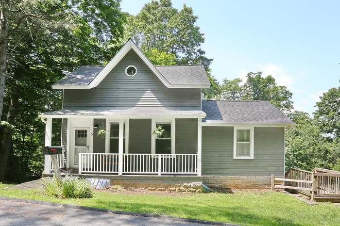 View of front of house featuring covered porch and a shingled roof