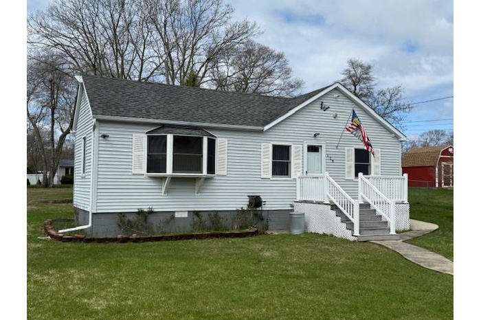 View of front of home featuring a front yard and roof with shingles