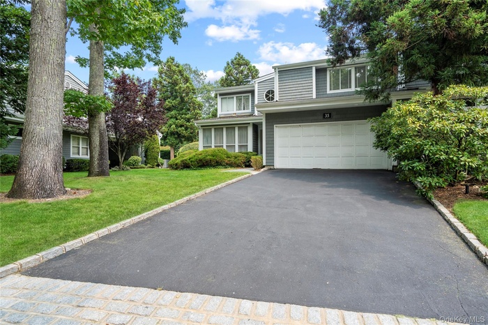 View of front of home featuring asphalt driveway, a front lawn, and an attached garage