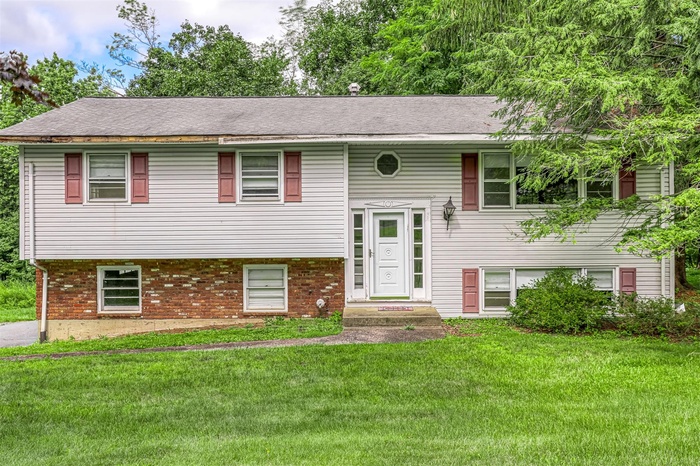 Bi-level home featuring brick siding and a front lawn