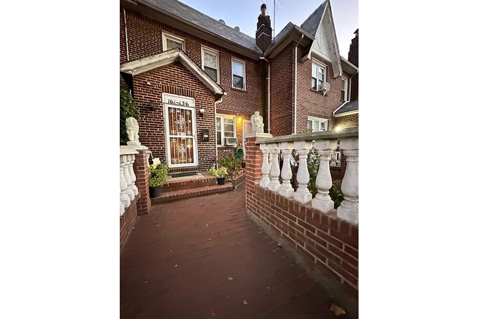 front view of house featuring brick siding and a chimney